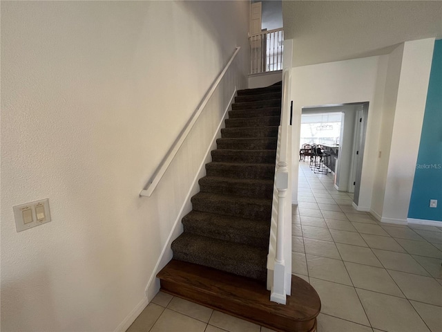 stairs with a high ceiling, tile patterned flooring, and baseboards