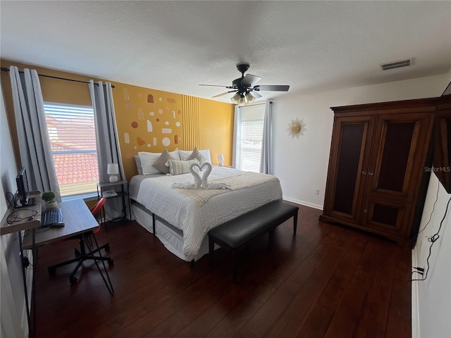 bedroom featuring visible vents, dark wood-type flooring, ceiling fan, a textured ceiling, and baseboards