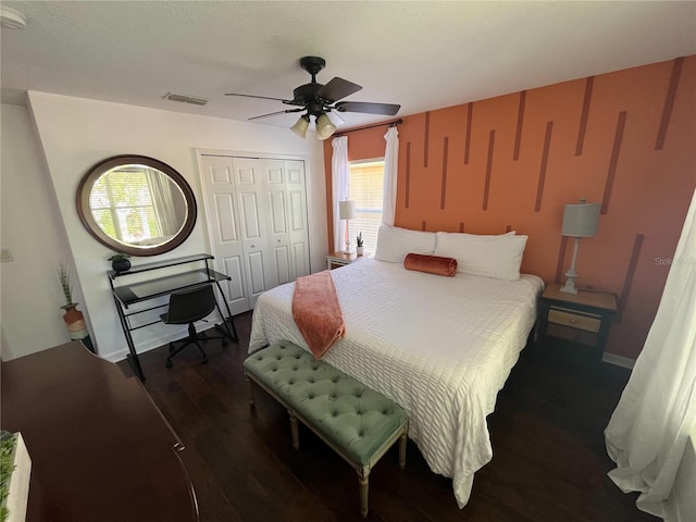 bedroom featuring baseboards, visible vents, a ceiling fan, dark wood-style flooring, and a closet