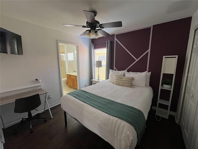 bedroom featuring ensuite bath, baseboards, ceiling fan, and wood finished floors