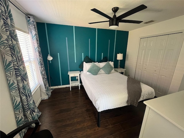 bedroom with ceiling fan, multiple windows, dark wood finished floors, and a closet