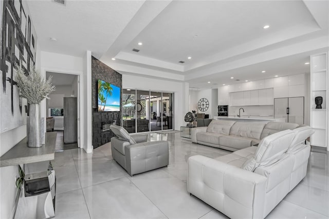living room with a tray ceiling and sink