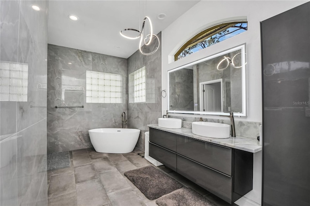 bathroom with vanity, a tub, and tile walls