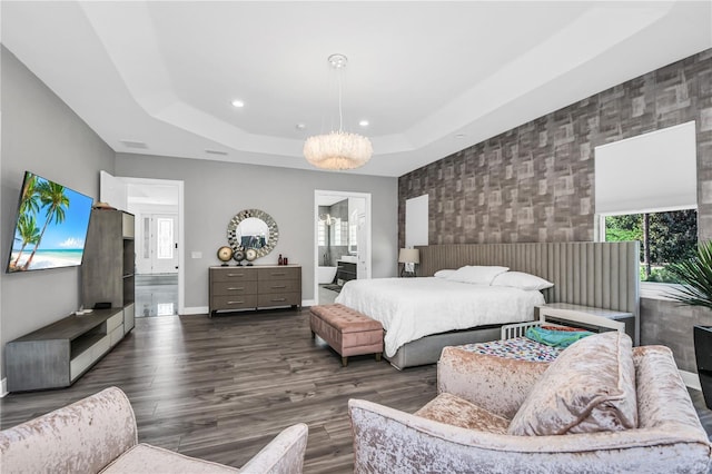 bedroom with ensuite bath, dark wood-type flooring, and a raised ceiling