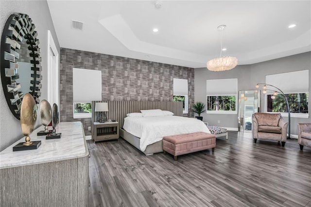 bedroom with a tray ceiling, hardwood / wood-style floors, and multiple windows