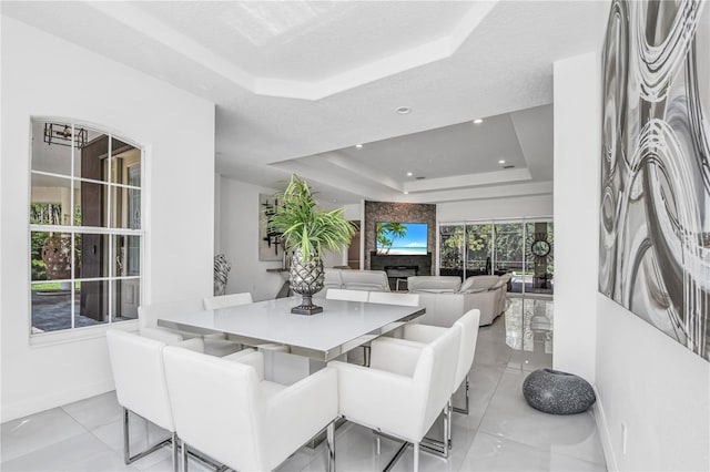 dining area with a large fireplace, a tray ceiling, and a textured ceiling
