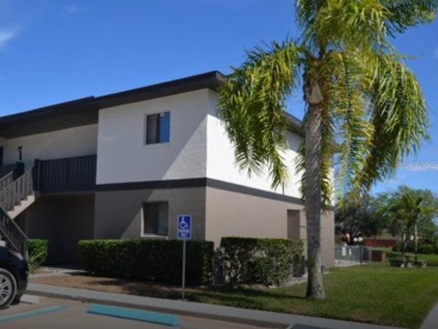 view of property featuring uncovered parking and stairway