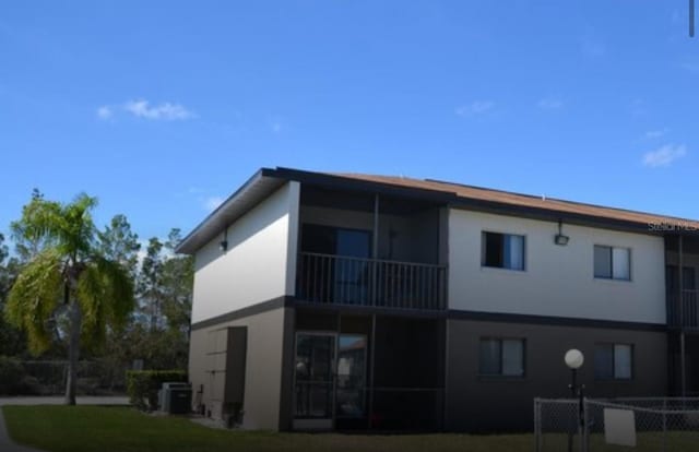 rear view of house featuring cooling unit and a lawn