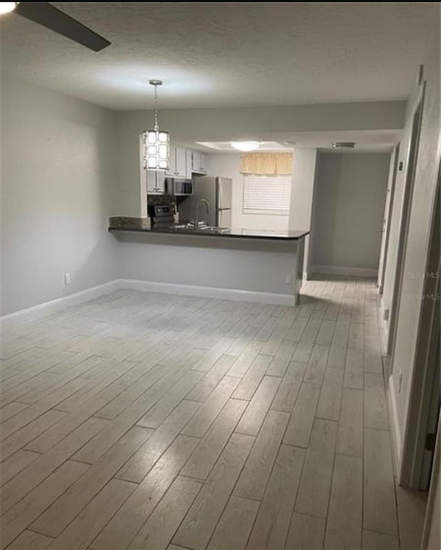 empty room with ceiling fan, light hardwood / wood-style flooring, sink, and a textured ceiling