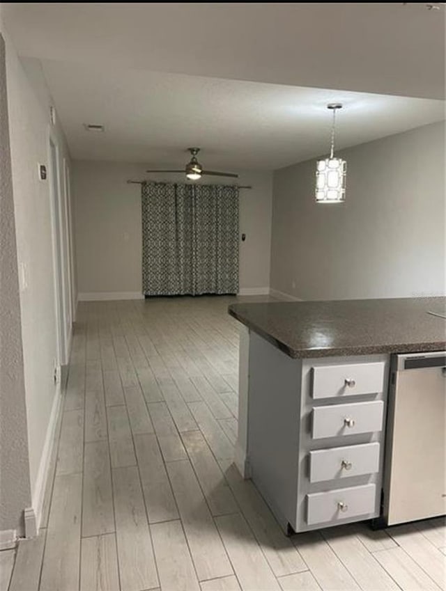 kitchen with dark countertops, stainless steel dishwasher, a ceiling fan, open floor plan, and light wood-type flooring