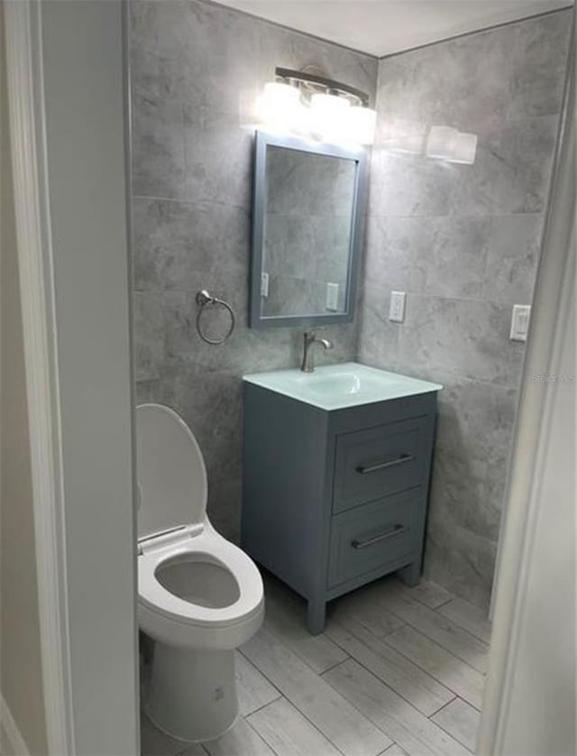 bathroom featuring vanity, wood-type flooring, and tile walls