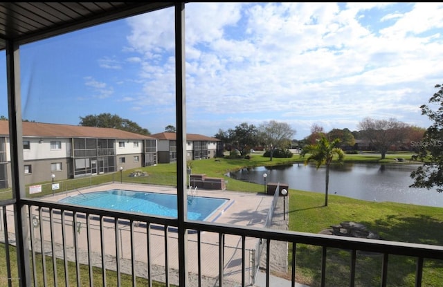 view of pool with a water view and a yard