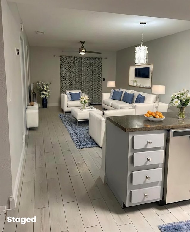 living area featuring light wood-style floors, visible vents, baseboards, and a ceiling fan