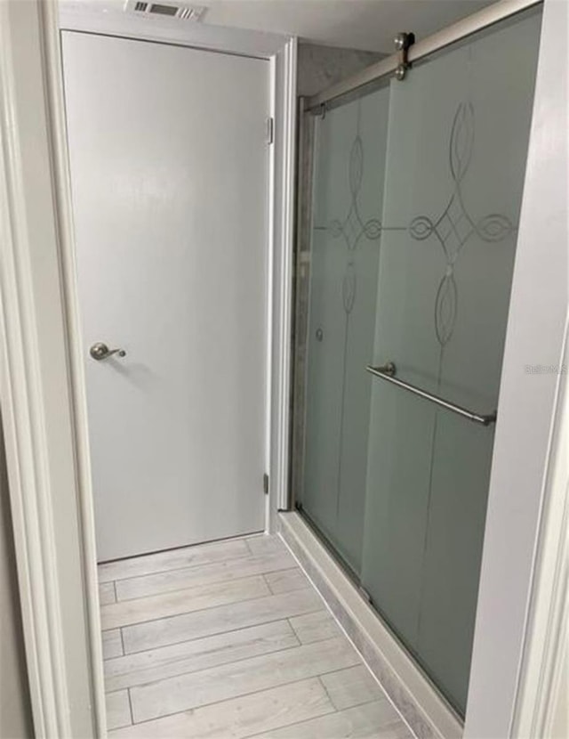 full bath with visible vents, a shower stall, and wood finished floors