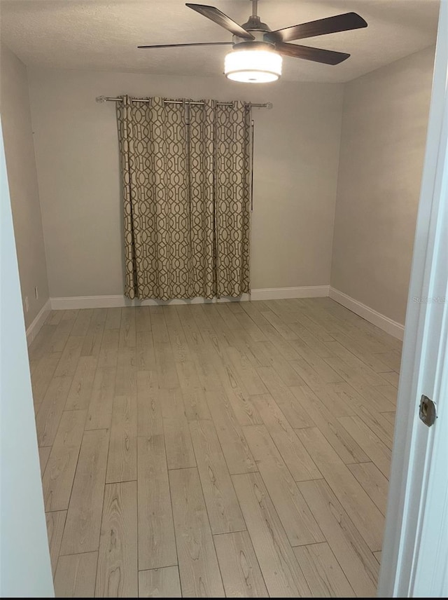 spare room with ceiling fan, baseboards, and wood finished floors