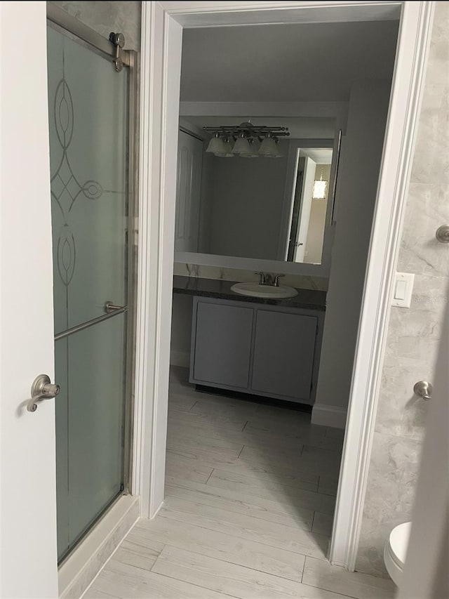 bathroom featuring toilet, a stall shower, wood finished floors, and vanity