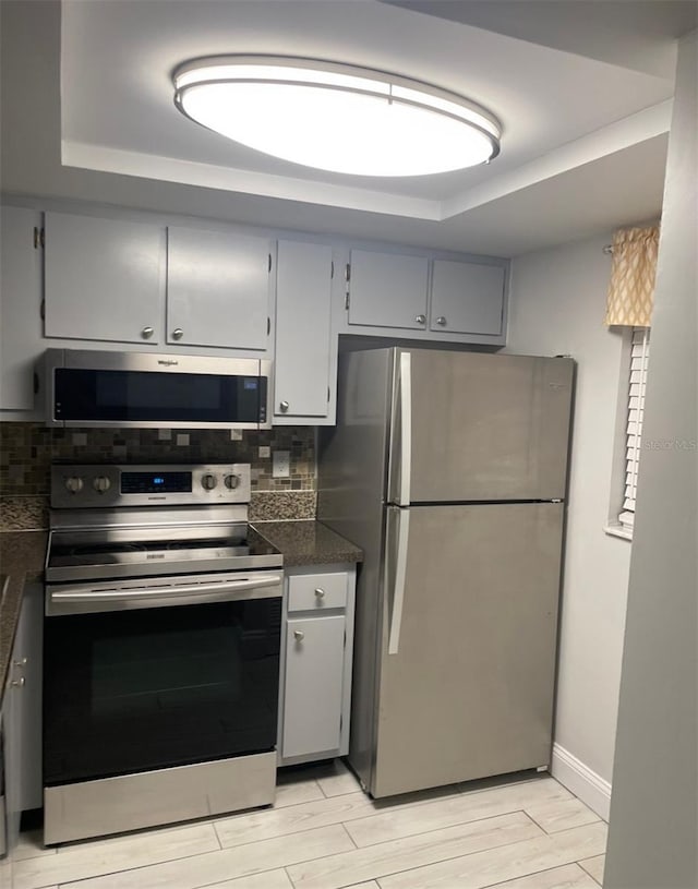 1804 University Ln Unit 308, Cocoa, FL 32922 - kitchen with stainless steel appliances, dark countertops, decorative backsplash, gray cabinetry, and a raised ceiling