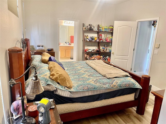 bedroom with ensuite bath and wood-type flooring