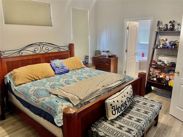 bedroom with connected bathroom and light hardwood / wood-style floors