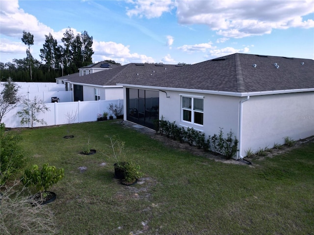 rear view of house with a lawn and a sunroom