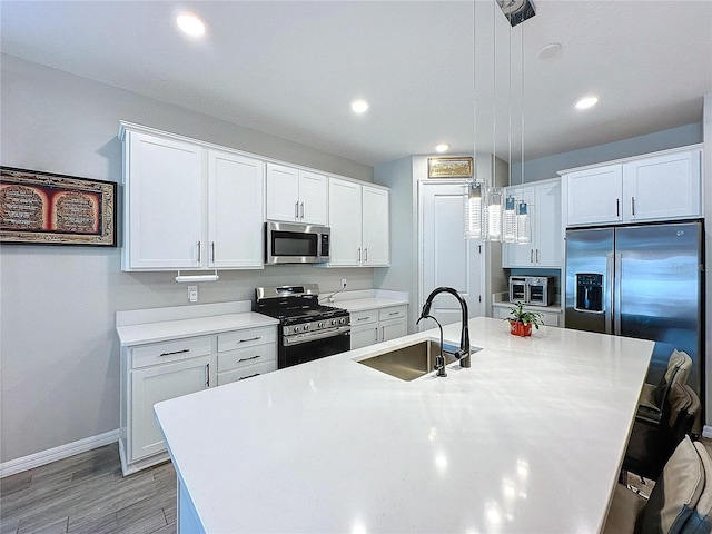 kitchen featuring sink, decorative light fixtures, a center island with sink, and appliances with stainless steel finishes