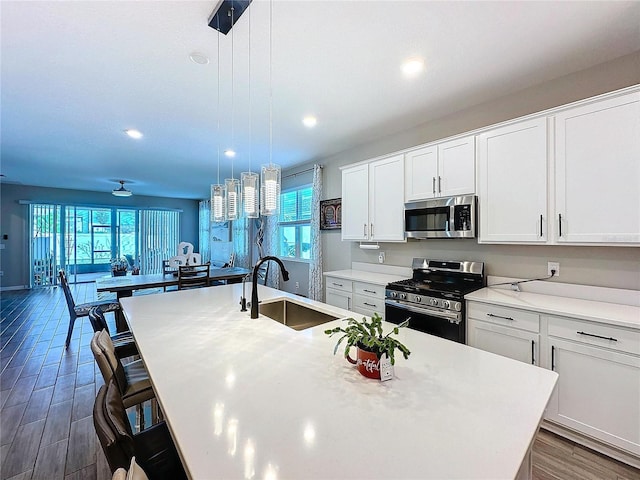 kitchen with pendant lighting, sink, a breakfast bar area, stainless steel appliances, and an island with sink