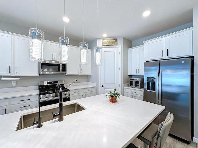 kitchen featuring hanging light fixtures, a kitchen bar, white cabinets, and appliances with stainless steel finishes