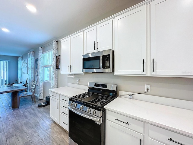 kitchen featuring white cabinetry, appliances with stainless steel finishes, and wood-type flooring