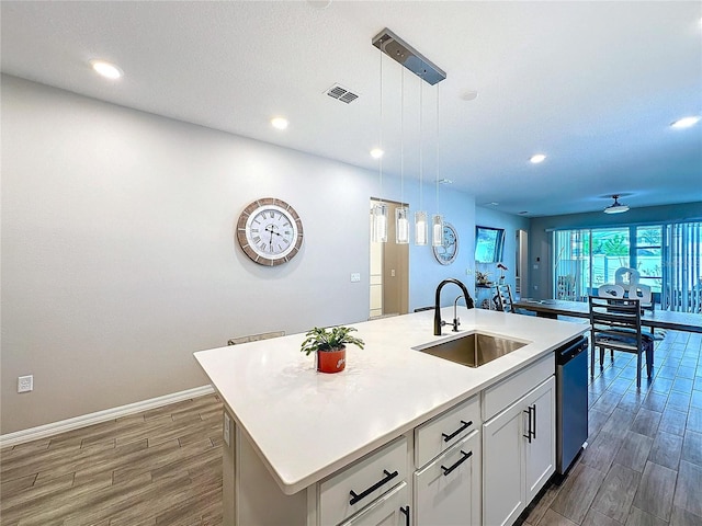 kitchen featuring sink, white cabinetry, hanging light fixtures, dishwasher, and a kitchen island with sink