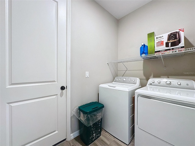 laundry area with separate washer and dryer and light hardwood / wood-style floors