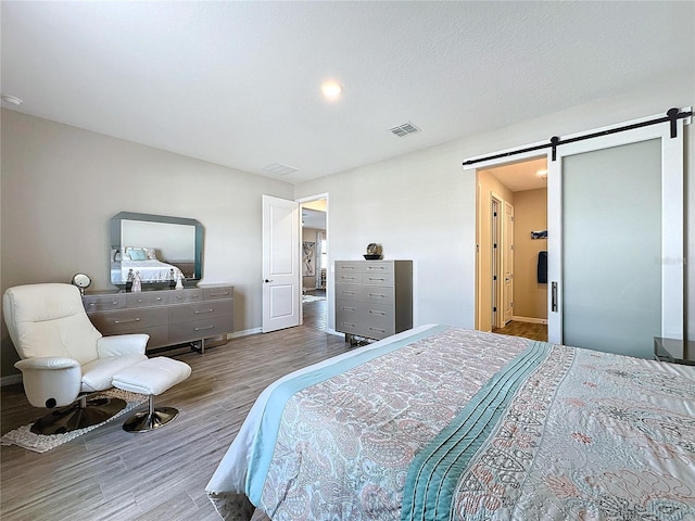 bedroom with hardwood / wood-style flooring, a barn door, and a textured ceiling