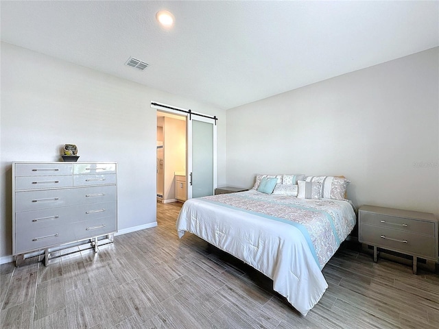 bedroom featuring wood-type flooring and a barn door