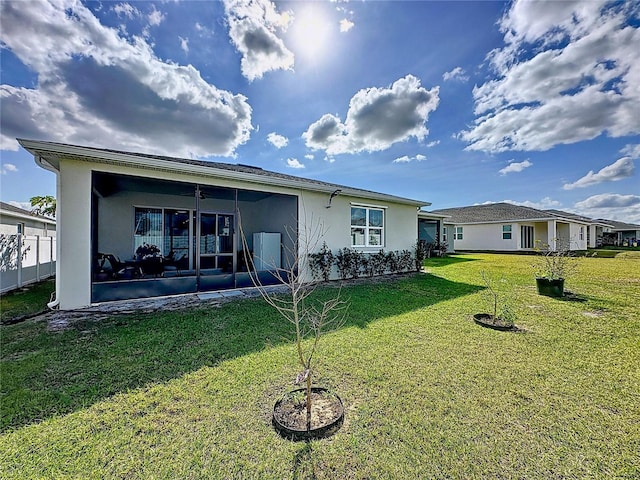 rear view of property featuring a sunroom and a lawn