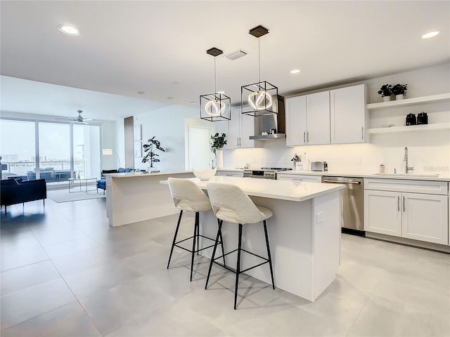 kitchen with sink, appliances with stainless steel finishes, a kitchen breakfast bar, white cabinets, and a kitchen island