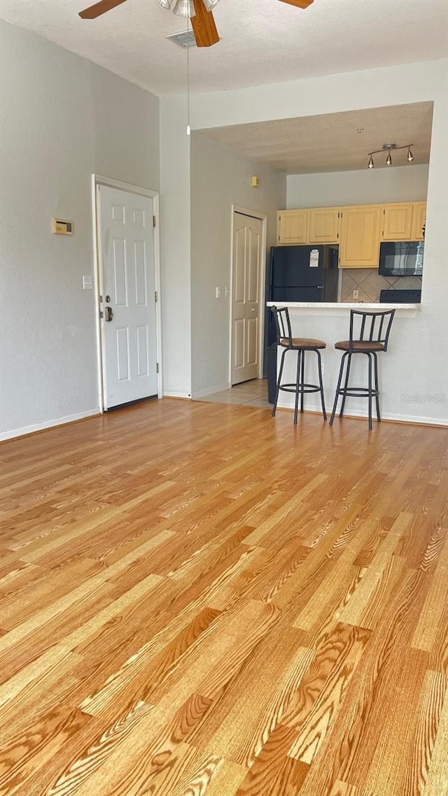 unfurnished living room featuring track lighting, ceiling fan, and light hardwood / wood-style floors