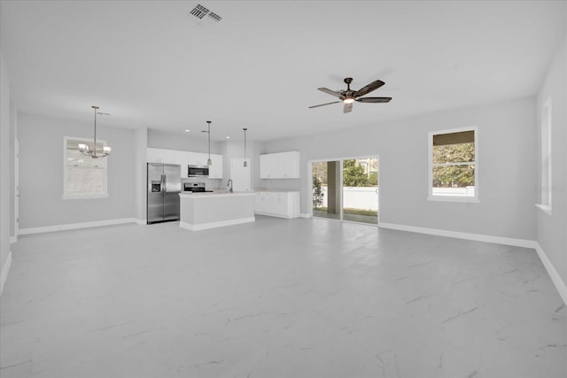 unfurnished living room with sink and ceiling fan with notable chandelier