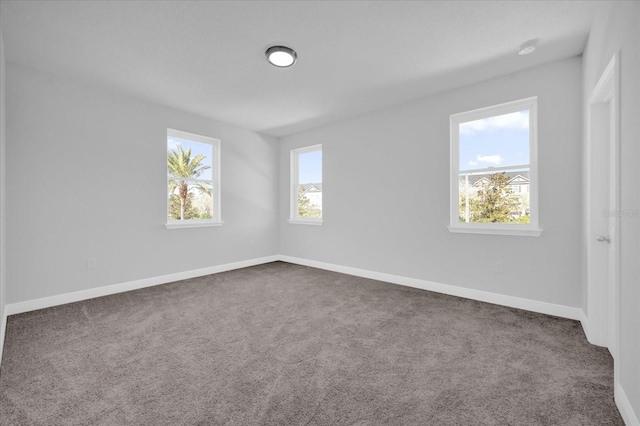 spare room with plenty of natural light and dark carpet