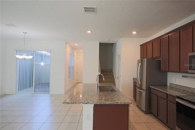 kitchen with sink, light tile patterned floors, appliances with stainless steel finishes, an island with sink, and light stone countertops