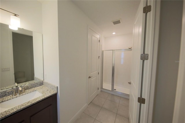 bathroom featuring vanity, a shower with shower door, tile patterned floors, and toilet