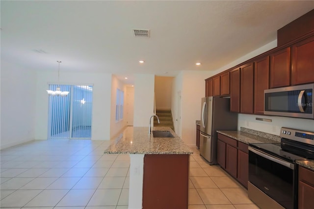 kitchen featuring sink, light tile patterned floors, a kitchen island with sink, stainless steel appliances, and light stone countertops