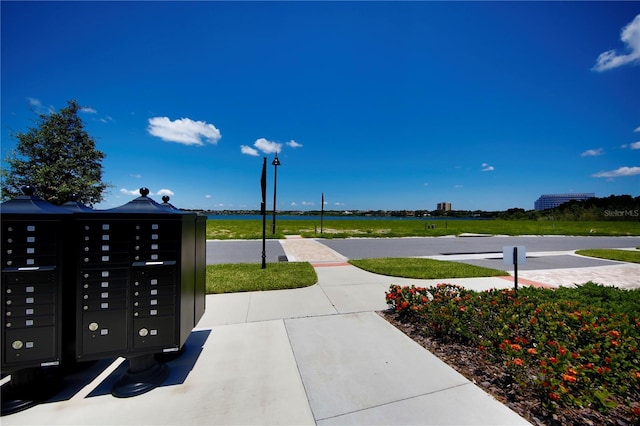 surrounding community with mail boxes and a water view