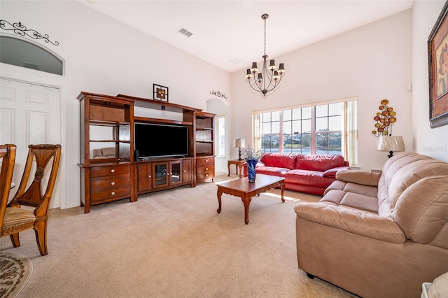 living room with a towering ceiling, light colored carpet, and a chandelier