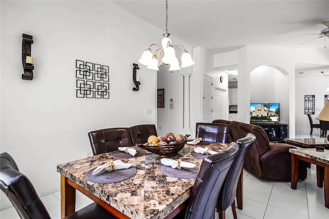 tiled dining space featuring ceiling fan with notable chandelier and lofted ceiling