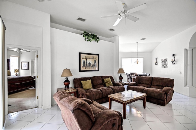 living room featuring ceiling fan with notable chandelier, light tile patterned floors, and decorative columns