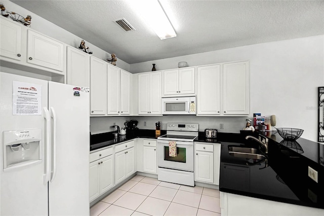 kitchen featuring white appliances, sink, light tile patterned flooring, a textured ceiling, and white cabinets