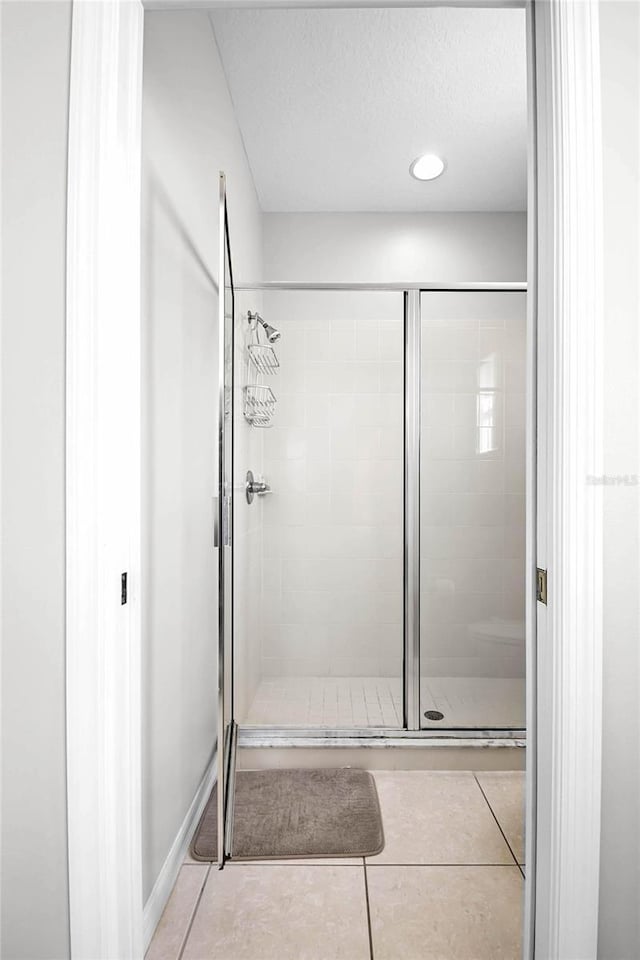 bathroom featuring tile patterned floors, an enclosed shower, and a textured ceiling