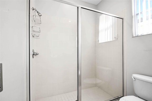 bathroom with a shower with door and toilet