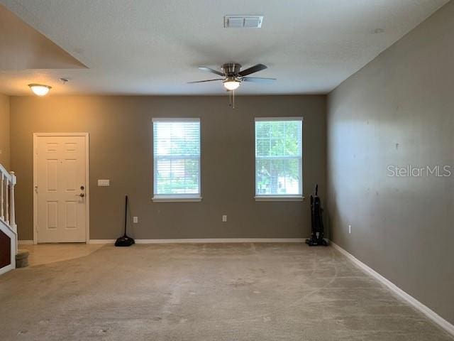 unfurnished room featuring stairway, light colored carpet, visible vents, and baseboards