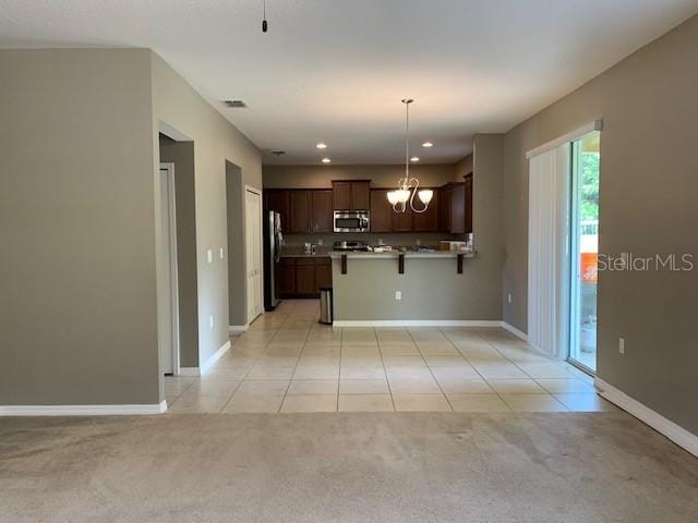 kitchen featuring stainless steel microwave, visible vents, open floor plan, light carpet, and freestanding refrigerator