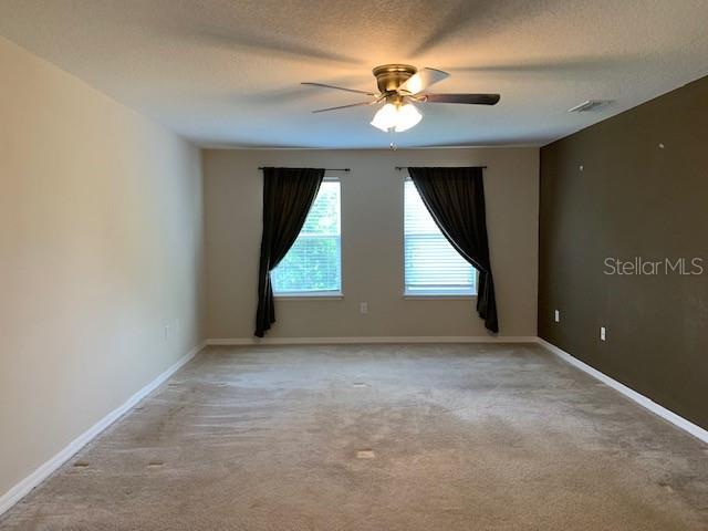 unfurnished room with baseboards, light carpet, a textured ceiling, and ceiling fan